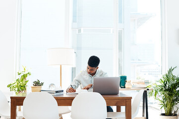 Canvas Print - Work hard until success happens. a young businessman using a laptop and going over paperwork in a modern office.