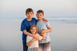 Three kids standing on beach at sunset. happy family, two school boys and one little preschool girl. Siblings having fun.