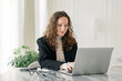 © muse studio - A business lady uses a laptop, a young woman in the office is sitting in stylish business clothes. A startup person is immersed in work.