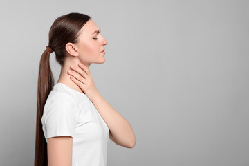 Poster - Young woman with sore throat on light grey background. Space for text