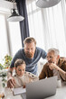 © LIGHTFIELD STUDIOS - Gay dads using laptop while daughter doing homework at home.