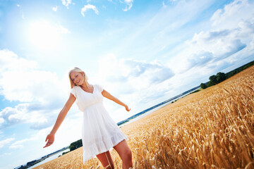 Wall Mural - Ive never felt more free. Happy young woman walking through a wheat field.