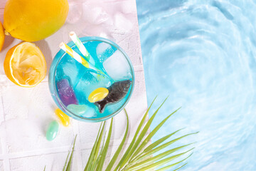 Wall Mural - Funny Fish bowl mocktail. Cold blue colored sour lemon Fishbowl Cocktail with rum, liqueur, citrus juice and jelly fish and stones candy 