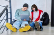 © Valerii Honcharuk - Friends hipster teenagers guy and girl sitting on floor with backpacks using laptop