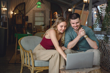 Wall Mural - A young man freelance and a beautiful white girl with a comfortable lifestyle working on a laptop computer in her studio Sit down and talk to each other and plan your work.