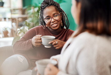 coffee, the official drink of girls night in. two young women having coffee and chatting on the sofa