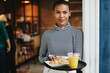© Flamingo Images - Friendly waitress standing with food in a cafe