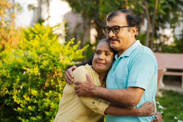 Wall Mural - Happy indian elderly senior woman embracing or hugging husband by holding closely with copy space - concept of companion, secure and comfortable