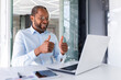 © Liubomir - Video call on online meeting, african american businessman boss talking to colleagues partners showing laptop camera thumbs up satisfied with team work achievement results.
