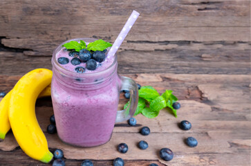 Wall Mural - Blueberry mix banana smoothies purple colorful fruit juice milkshake blend beverage healthy high protein taste yummy drink in glass morning on wooden background.