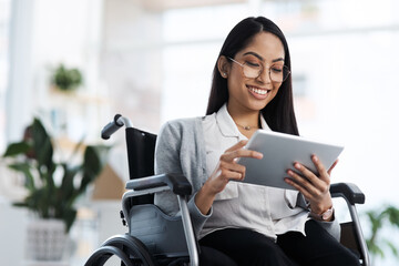 Wall Mural - Happy and successful. an attractive young businesswoman in a wheelchair using her tablet in the office.