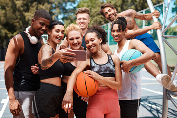  Gather around for a team selfie. a group of sporty young people taking selfies together on a sports court.
