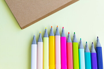 A lot of colorful felt-tip pens for drawing in a notebook and album on a yellow background.