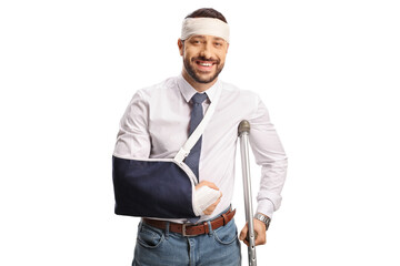 Wall Mural - Young man with a broken arm and bandage on head leaning on a crutch and smiling