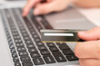 © Diomedes de jesus - Close up of hand holding a black debit card front the laptop while a hand are typing in the keyboard