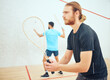 © D Lahoud/peopleimages.com - Young athletic squash player getting ready for playing opponent in competitive court game. Fit active caucasian athlete looking focused during training challenge in sports centre. Waiting for serve