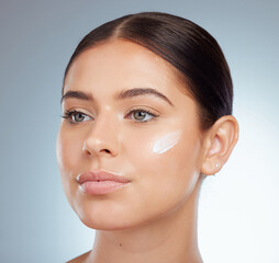 Sticker - Closeup of beautiful woman with face cream on her cheek posing with copyspace. Caucasian model isolated against grey studio background with product. Moisturise and sunscreen for healthy skincare