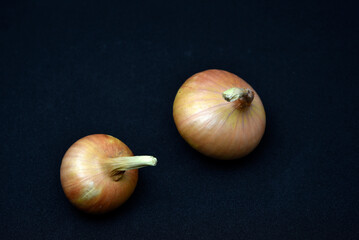 Wall Mural - Two bulbs on a black background. Vegetables close-up.