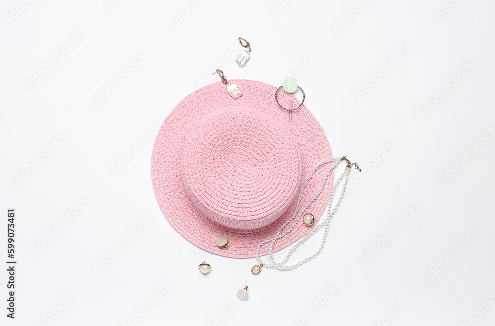Pink straw hat with jewelry on white background