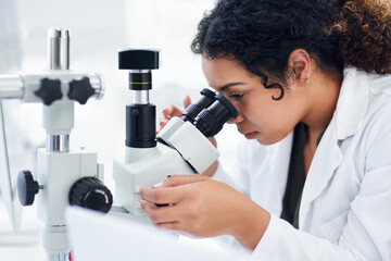 Aufkleber - Taking a closer look. a young female scientist using a microscope in a laboratory.