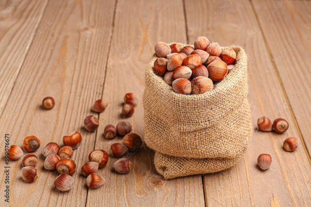 Sack bag with shelled hazelnuts on wooden background
