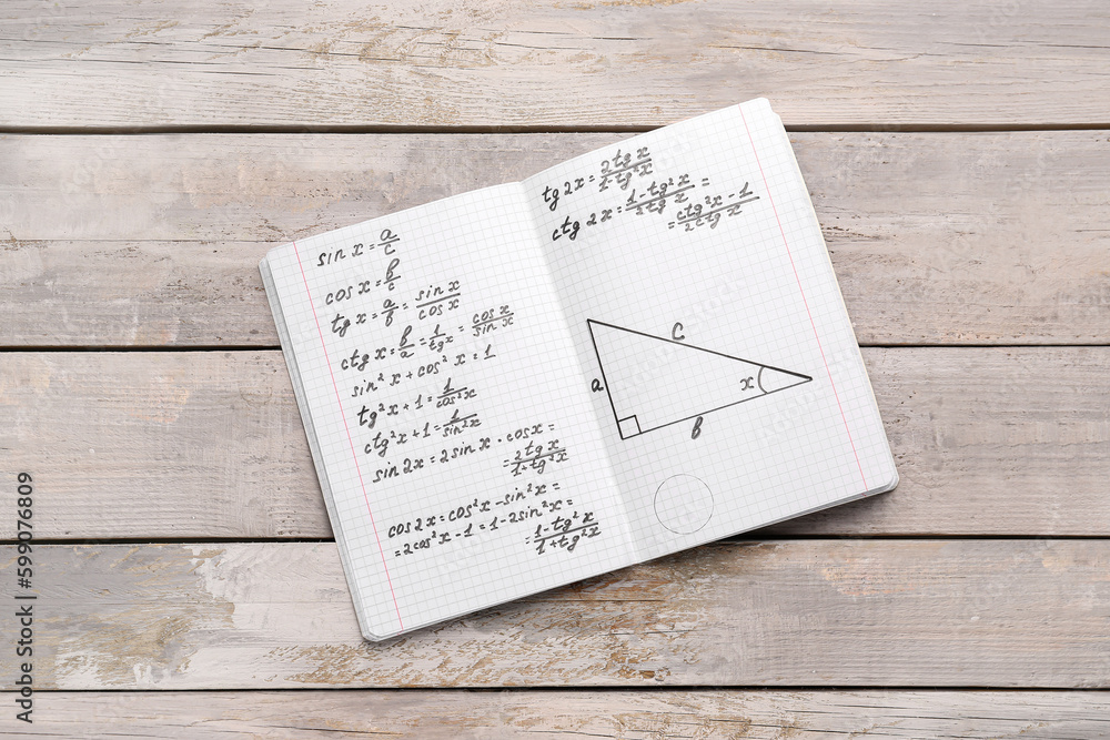 Copybook with maths formulas on grey wooden background