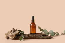 Bottle Of Cosmetic Oil With Eucalyptus Branches And Tree Bark On Pale Pink Background