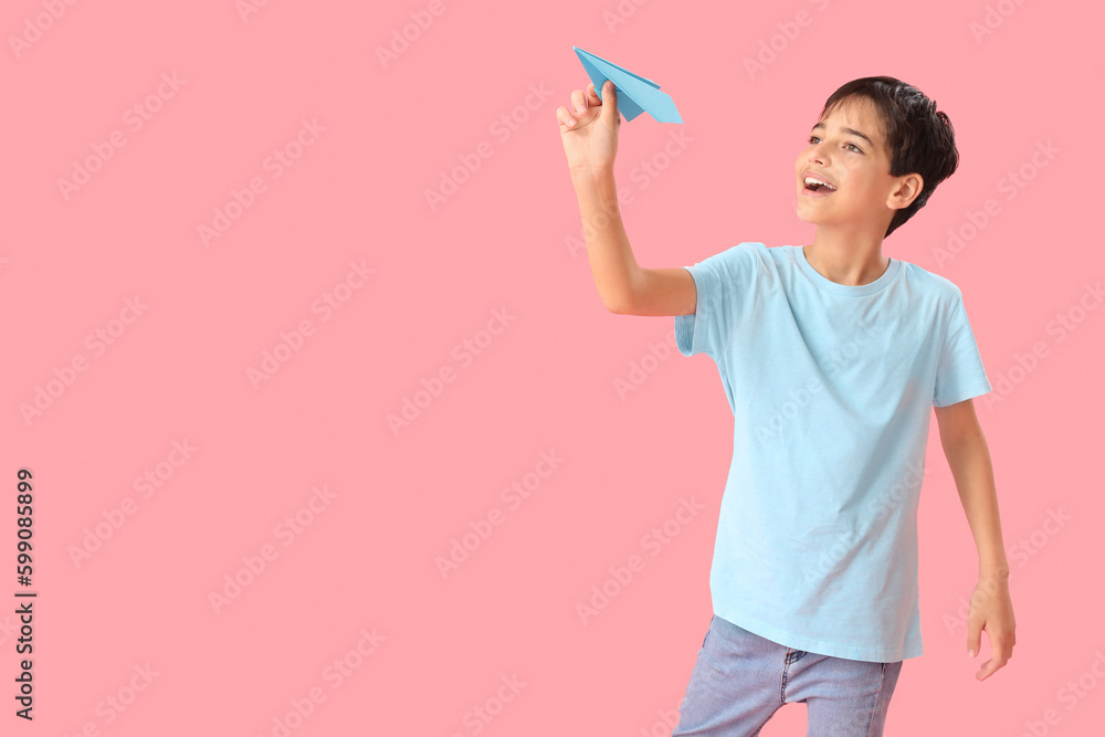 Little boy with paper plane on pink background. Children's Day celebration