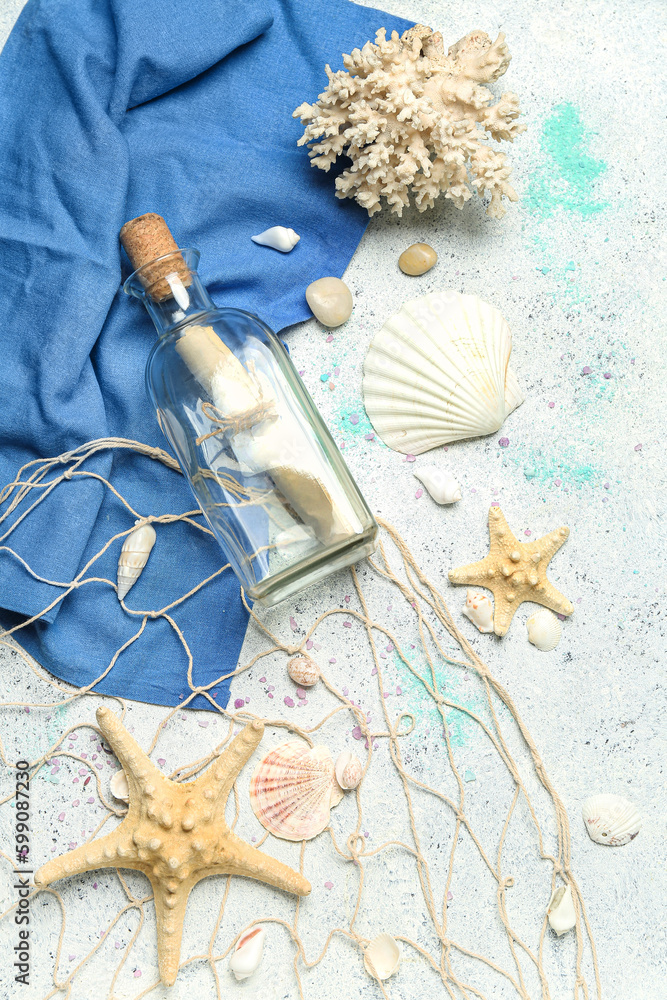 Bottle with letter, sea shells, starfishes and net on grunge background