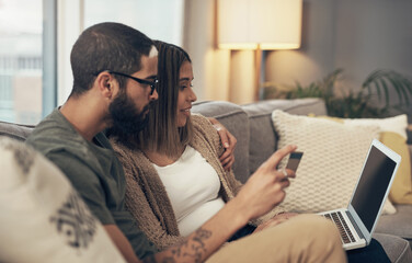 Sticker - The best site for budget conscious shoppers. a young couple using a laptop and credit card on the sofa at home.