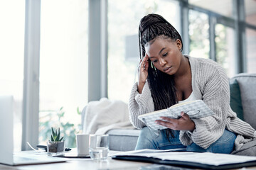 Sticker - Money talksit also walks. a young woman going over paperwork on the sofa at home and looking worried.