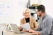 © New Africa - Boss and employee with laptop discussing work issues at wooden table in office