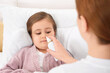 © New Africa - Mother using nasal spray to treat her little daughter on bed