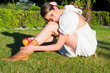 Biting apple concept. Portrait of a young woman eating apple isolated on green grass in summer park. Healthy apple fruit for natural vitamin, dieting and vegan. Outdoor portrait of sexy girl eat green