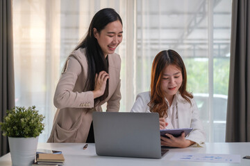 Image of female colleagues working together with laptop, discussing marketing plan at co working space.