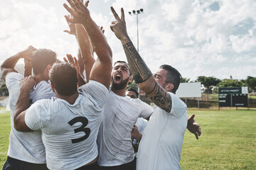 Wall Mural - We are the best. a group of cheerful young rugby players celebrating their win after a match outside during the day.