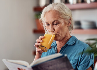 Sticker - Getting lost in a good book. an attractive senior woman enjoying a glass of orange while reading a book in her kitchen at home.