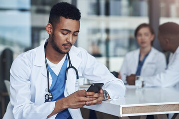 Wall Mural - that was such a beautiful message. a young male doctor using his smartphone while taking a break.