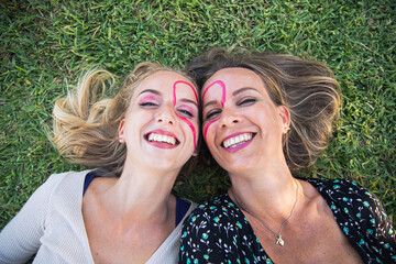 Portrait of smiling mother and daughter together with a heart drawn on their faces