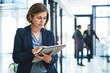 © Grady R/peopleimages.com - Smart technology has you covered. an attractive young businesswoman using a digital tablet in an office with her colleagues in the background.