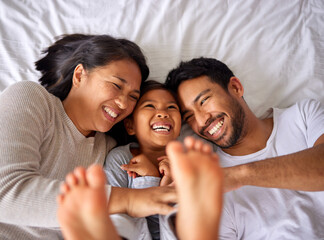 Wall Mural - Family of three laughing and having fun while lying in a bed together