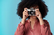 © Nicholas Felix/peopleimages.com - Living life one click at a time. Studio shot of a young woman using a camera against a blue background.