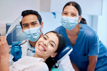 Wall Mural - They always do the most amazing job. a young woman checking her results in the dentists office.