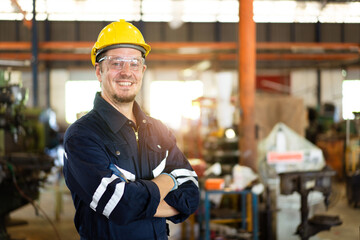 Professional caucasian white ethnicity male technician operating the heavy duty machine in the lathing factory. Technician in safety and helmet suit controlling a machine in factory.