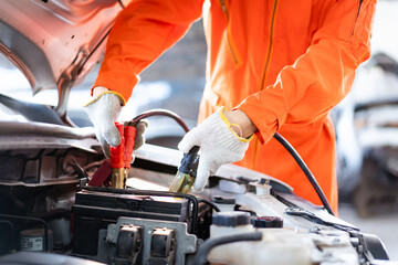 Professional roadside technician support using an emergency jump start cable to connect a battery from other car to the one which out of battery. 