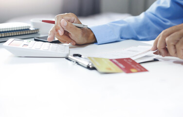 Wall Mural - Asian businessman checking invoice and use calculator to calculate cost from online order, A man start new business online and using a credit card to pay for order