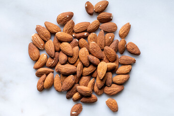 Wall Mural - Heap of fresh almonds on white marble background. Top view. Close-up.