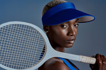 I let the racket do the talking. Studio shot of a sporty young woman posing with a tennis racket against a grey background.
