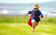 © Alexandra W/peopleimages.com - Young boy, costume and running in park, playing and carefree outdoor with happiness or playful child on grass. Freedom, energy or youth and happy kid in cape or goggles fun on green lawn with mockup