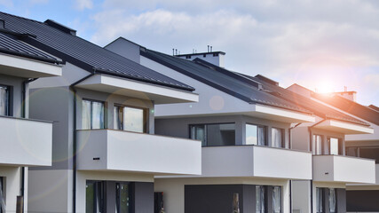 Terraced family homes in newly developed housing estate. The real estate market in the suburbs. New single family houses in a new development area. Residential homes with modern facade. 